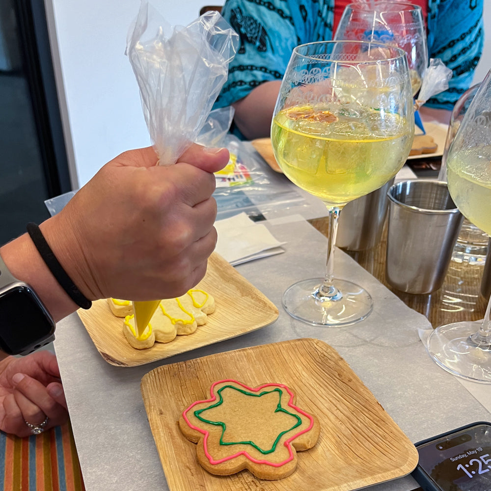 Person decorating cookies with a glass of Limoncello Spritz on the table