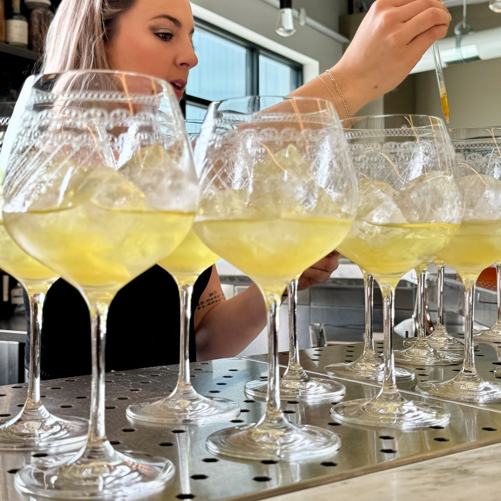 Woman adding bitters to glasses with limoncello