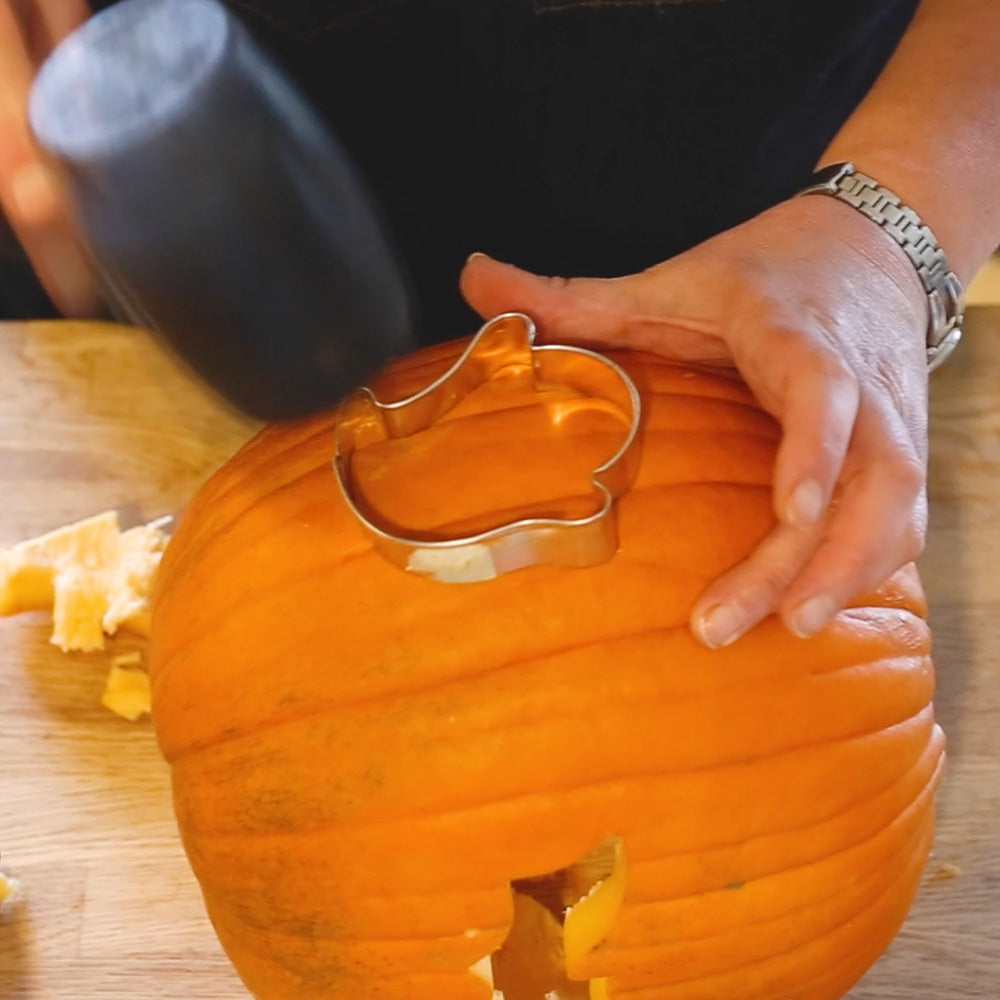 Using a ghost cookie cutter to carve a pumpkin