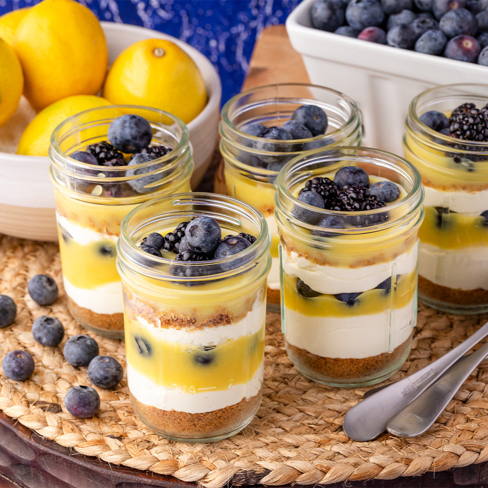 Jars of lemon curd parfait topped with berries.