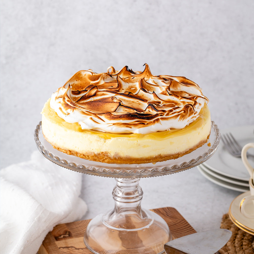 Meringue topped cheesecake on a glass cake stand