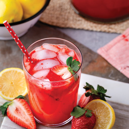 Glass of strawberry lemonade surrounded by strawberries and lemons