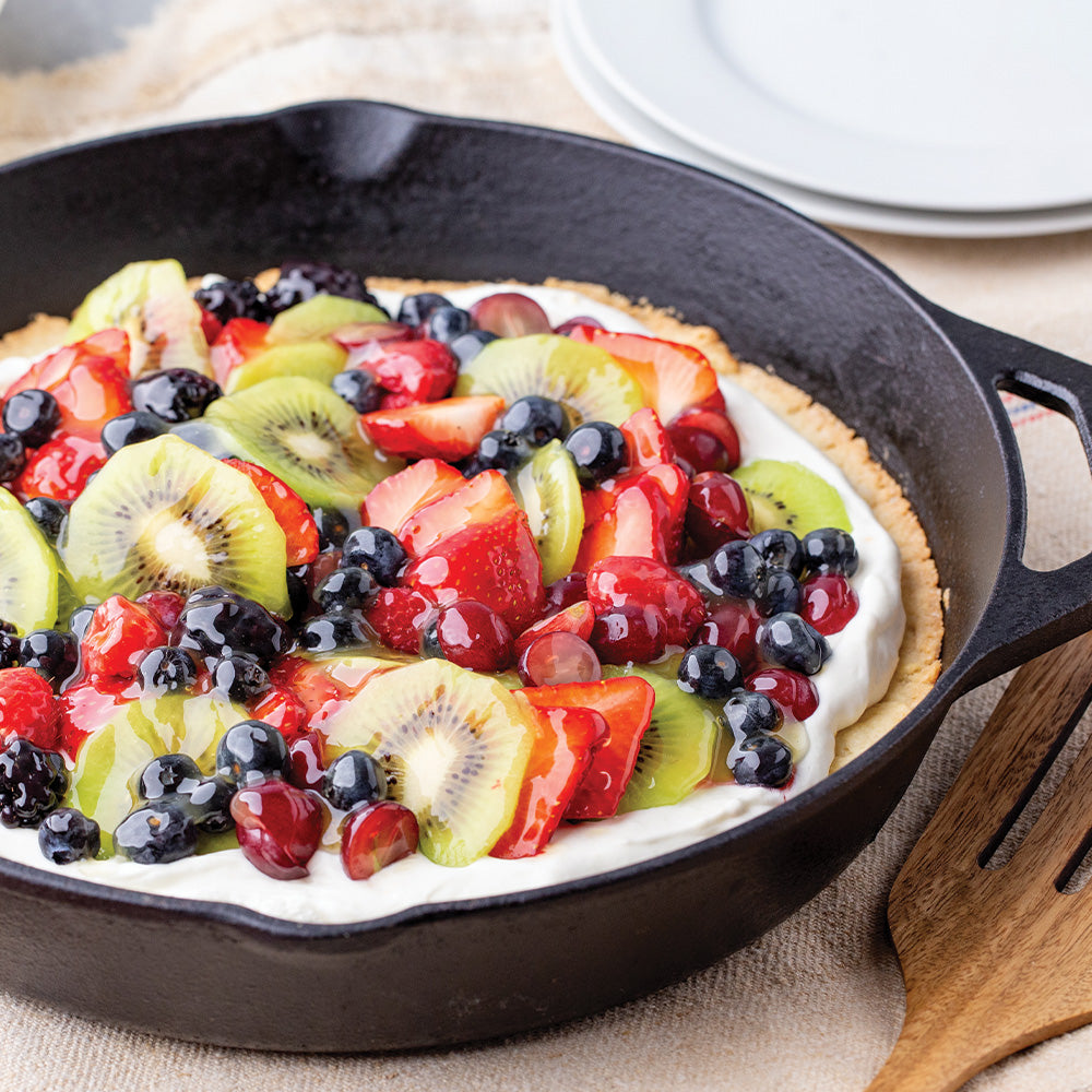 Skillet with a cookie crust pizza topped with fresh fruit